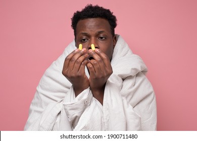 African Young Man Holding A Yellow Earplug Trying To Sleep Having Insomnia. Studio Shot