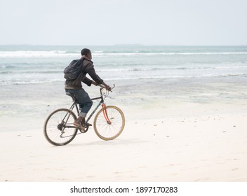 African Young Man Riding Bike On Tropical Beach