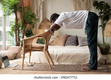 African young man working out, practicing yoga, standing in Ardha Uttanasana
