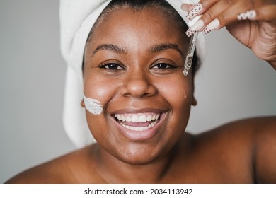 African young woman applying hyaluronic drop and skin mask beauty treatment on her face - Focus on dropper - Powered by Shutterstock