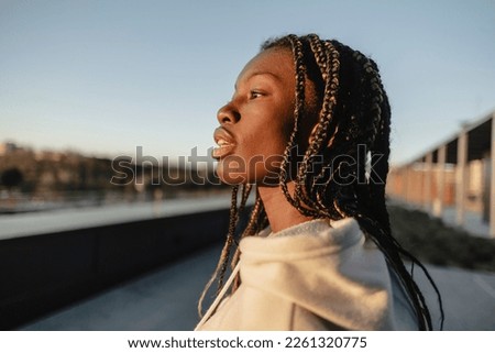 African young woman with dreadlocks, in profile contemplating the city.