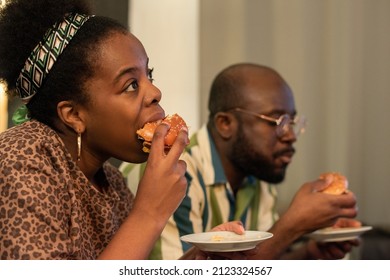 African Young Woman Eating Burger Together With Her Boyfriend For Watching The Movie At Home