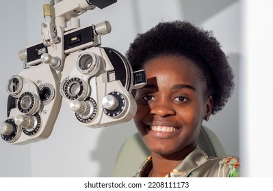 African young woman girl doing eye test checking examination in clinic or optical shop, sitting at phoropter equipment. Eyecare concept. - Powered by Shutterstock