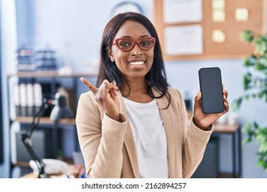 African Young Woman Holding Smartphone Showing Blank Screen Smiling Happy Pointing With Hand And Finger To The Side 