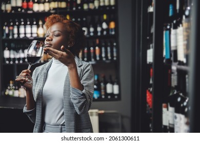 African Young Woman Sommelier Holds Glass With Red Wine, Buy Alcohol At Supermarket.