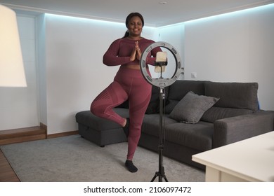 African young woman vlogger records yoga tutorials with her phone at home. - Powered by Shutterstock