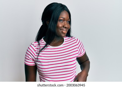 African Young Woman Wearing Casual Striped T Shirt Looking To Side, Relax Profile Pose With Natural Face And Confident Smile. 