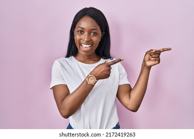 African Young Woman Wearing Casual White T Shirt Smiling And Looking At The Camera Pointing With Two Hands And Fingers To The Side. 