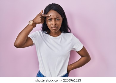 African Young Woman Wearing Casual White T Shirt Pointing Unhappy To Pimple On Forehead, Ugly Infection Of Blackhead. Acne And Skin Problem 