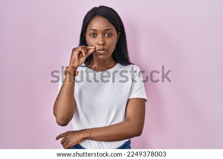 African young woman wearing casual white t shirt mouth and lips shut as zip with fingers. secret and silent, taboo talking 