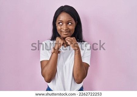 African young woman wearing casual white t shirt laughing nervous and excited with hands on chin looking to the side  Foto d'archivio © 