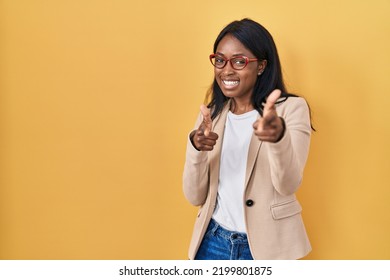 African young woman wearing glasses pointing fingers to camera with happy and funny face. good energy and vibes.  - Powered by Shutterstock