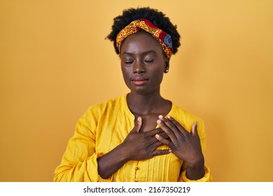 African Young Woman Wearing African Turban Smiling With Hands On Chest With Closed Eyes And Grateful Gesture On Face. Health Concept. 