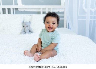 African-American baby smiles or laughs while sitting on the bed at home