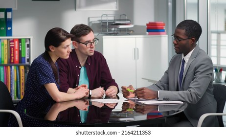 African-American Bank Manager Explain Mortgage Details To Couple Of Clients. Young Husband And Wife Visit Insurance Specialist In Modern Office