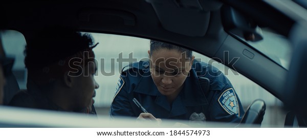 African-American black driver is being pulled off\
by mixed-race female police officer. Documents check, speeding\
ticket