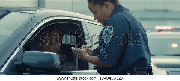 African-American black driver is being pulled off\
by mixed-race female police officer. Documents check, speeding\
ticket
