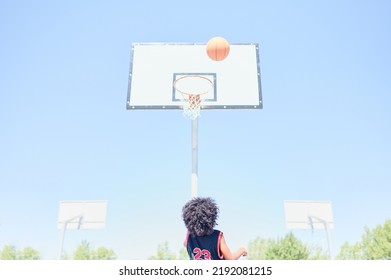 African-American boy waits for the ball to bounce off the backboard after a missed shoot in a basketball game on a court at a sports facility. Healthy life concept.