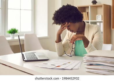 African-American business woman who is tired of work routines and deadlines suffers from headaches at work. Exhausted female office worker suffers from burnout. Concept of overworked. - Shutterstock ID 1984452932