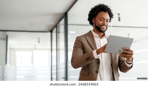 African-American businessman fully engaged with his tablet, illustrating the importance of technology in modern business strategy. His focused demeanor indicates serious engagement with his work. - Powered by Shutterstock