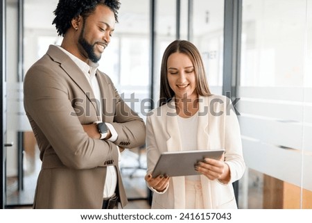 An African-American businessman and his colleague are absorbed in reviewing content on a tablet, showcasing a collaborative approach to digital information sharing