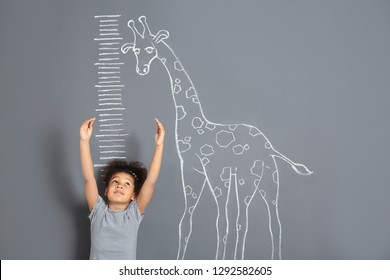 African-American Child Measuring Height Near Chalk Giraffe Drawing On Grey Background