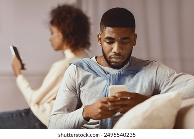 African-american couple ignoring each other, using cellphones on sofa - Powered by Shutterstock