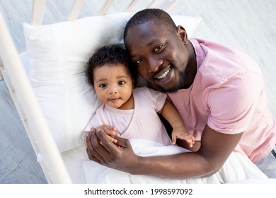 African-American Dad Hugs Baby Son In Crib Before Bedtime