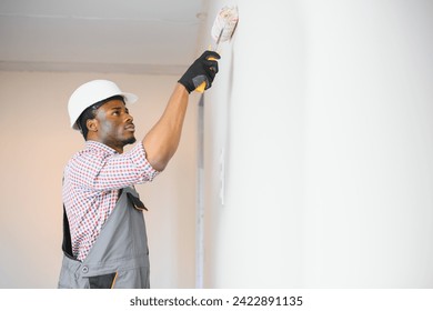 African-American decorator painting light wall. - Powered by Shutterstock