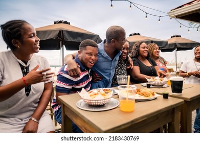 African-American Family Enjoying A Meal At A Beach Restaurant.