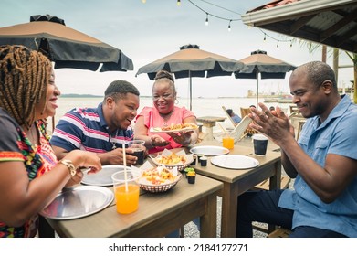 African-American Family Enjoying A Meal At A Beach Restaurant.