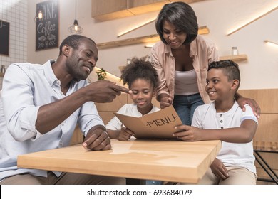 african-american family looking at menu list in cozy cafe - Powered by Shutterstock