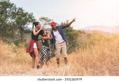 African-American Father, Mother and girl daughter using binocular while trekking on mountain at outside on holiday. Beautiful Black African family traveling in autumn field outdoor