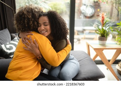An African-American female psychotherapist comforts the teenage female patient by hugging her. She is smiling because they have made progress. Both of them have the afro hairstyle. - Shutterstock ID 2218367603