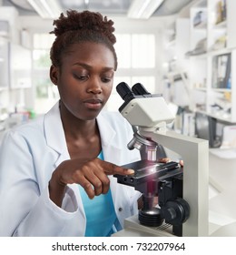 African-american Female Scientist, Student Or Tech In Lab Coat Works In Modern Laboratory With A Microscope