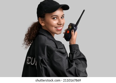 African-American female security guard with radio transmitter on light background