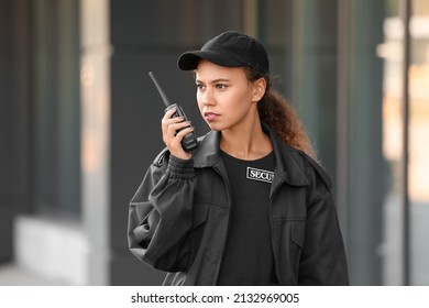 African-American female security guard with radio transmitter near building outdoors