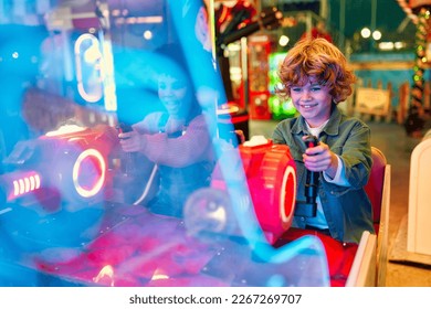 An African-American girl child with an Afro hairstyle and a cute Caucasian boy sitting in an amusement car ride playing a computer game racing in an amusement park.