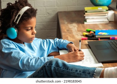 African-American girl doing homework,making notes,using headphones and laptop at home.Back to school concept.School distance education at home,home schooling,e-learning,diverse people.  - Powered by Shutterstock