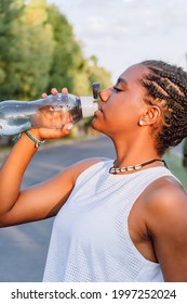 african-american girl drinking water after exercising on a sunny day - Shutterstock ID 1997252024