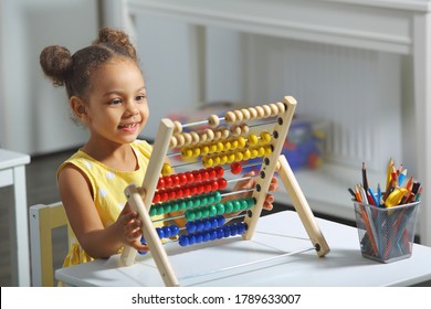 an african-american girl sits at a table and counts on an abacus and smiles - Shutterstock ID 1789633007