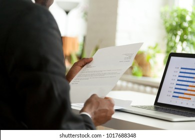 African-american hr manager or employer reading cover letter from job vacancy applicant, black businessman holding business mail checking paper correspondence at workplace, over the shoulder view - Shutterstock ID 1017688348