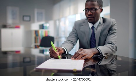 African-American Investor Sign Contract Sitting At Desk In Modern Workplace With Blurred Background. Successful Lawyer Prepare Documents For Clients