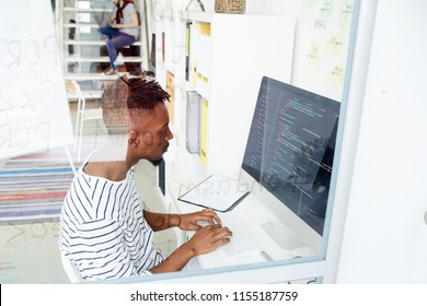 African-american it-specialist looking attentively at coded data on computer screen while working in office