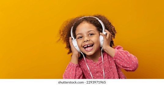 An African-American little girl with headphones listens to music expressing real emotions. - Powered by Shutterstock