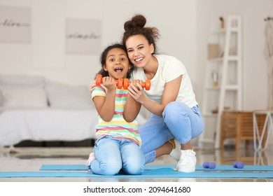 African-American little girl and her mother with dumbbells at home