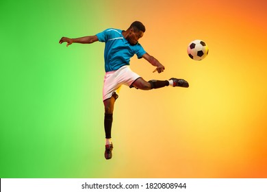 African-american male soccer, football player training in action isolated on gradient studio background in neon light. Concept of motion, action, ahievements, healthy lifestyle. Youth culture. - Powered by Shutterstock