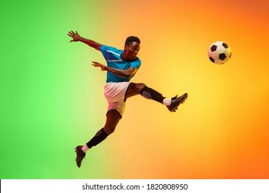 African-american male soccer, football player training in action isolated on gradient studio background in neon light. Concept of motion, action, ahievements, healthy lifestyle. Youth culture. - Powered by Shutterstock