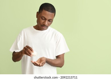 African-American Man With Fish Oil On Color Background