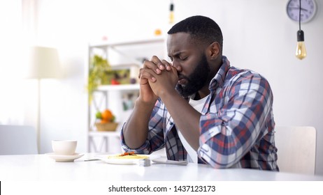 African-American man praying before lunch, thanking God for meal, religion